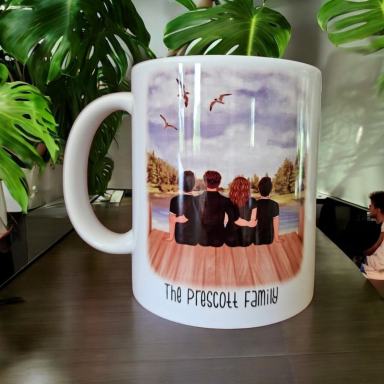 A mug featuring four people sitting by a lake, with trees and birds in the background.