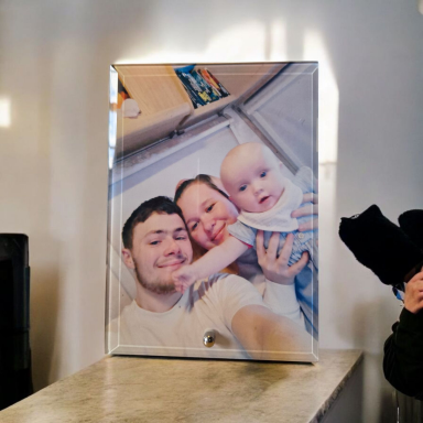 A family photo featuring a man, a woman, and a baby smiling together.